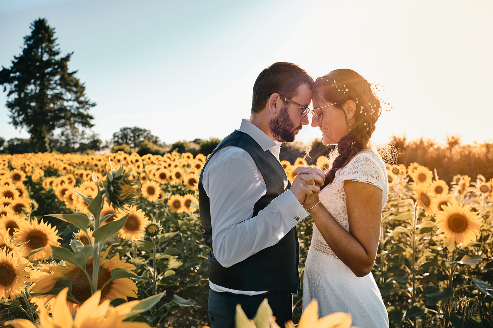 Mariés dans un champ de tournesol durant leur mariage champêtre
